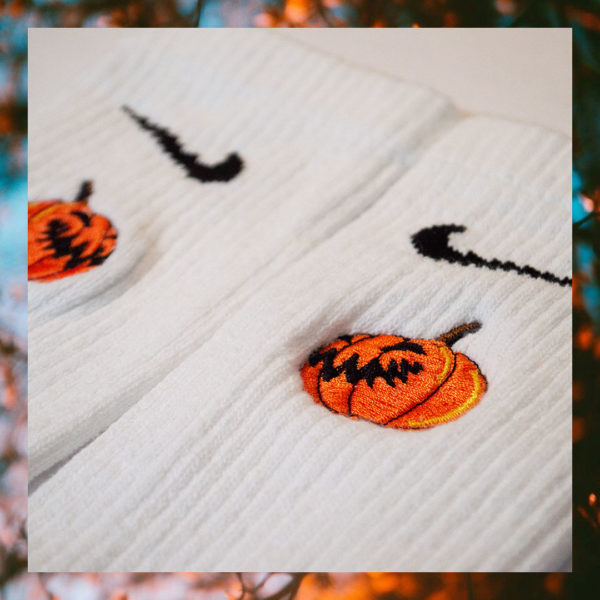 Pair of white crew socks featuring an embroidered jack-o-lantern